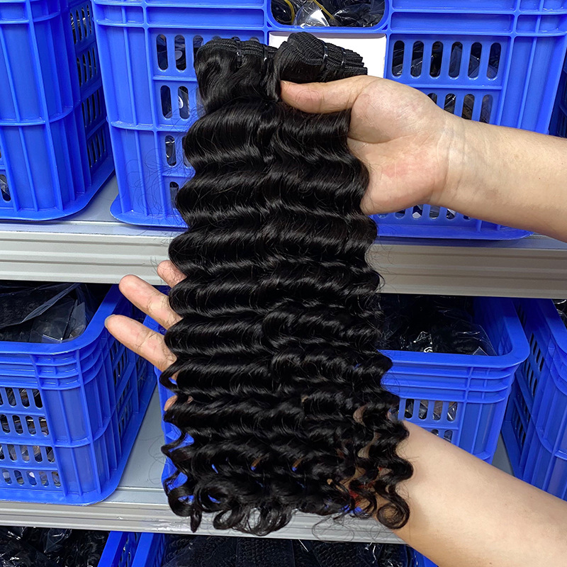 Scarlett Hair Deep wave hair extensions in black, held in hands over blue crates