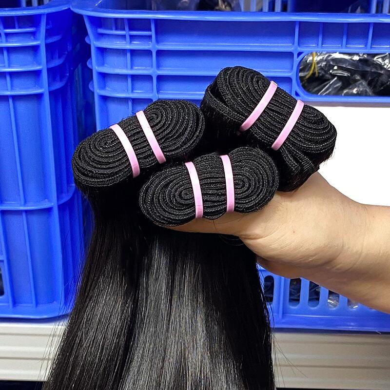 Scarlett Hair Bundles of black hair extensions held in a hand, with blue plastic crates in the background.